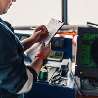 Marine navigational officer or chief mate on navigation watch on ship or vessel. He fills up checklist. Ship routine paperwork; Shutterstock ID 1225757410; purchase_order: -; job: -; client: -; other: -